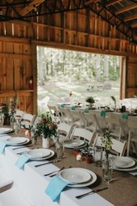 Boho wedding reception table settings in barn